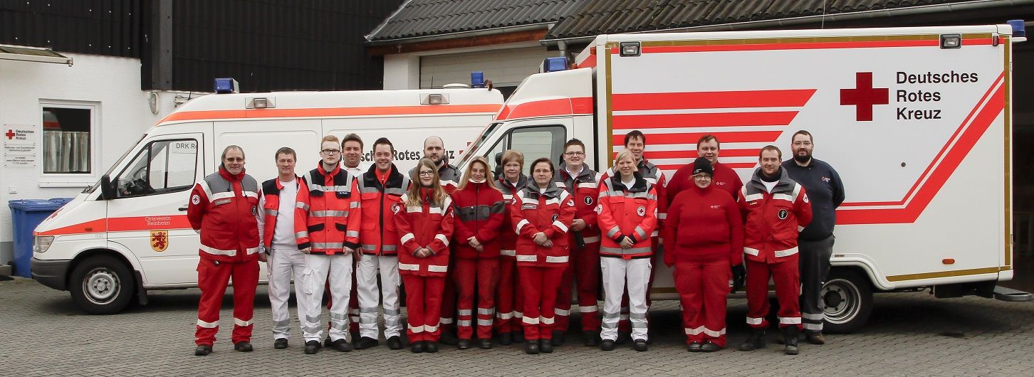 Foto: Zu sehen ist ein DRK-Rettungswagen von vorne in schneller Fahrt. Fahrer und Beifahrer konzentrieren sich auf die Fahrt.
