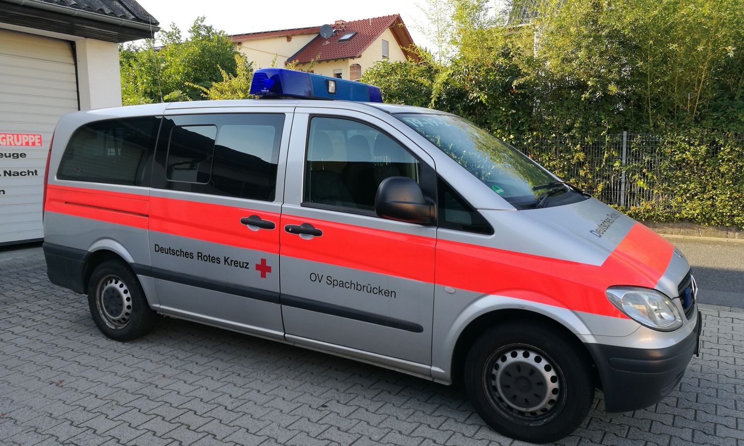 Foto: Zu sehen ist ein DRK-Rettungswagen von vorne in schneller Fahrt. Fahrer und Beifahrer konzentrieren sich auf die Fahrt.