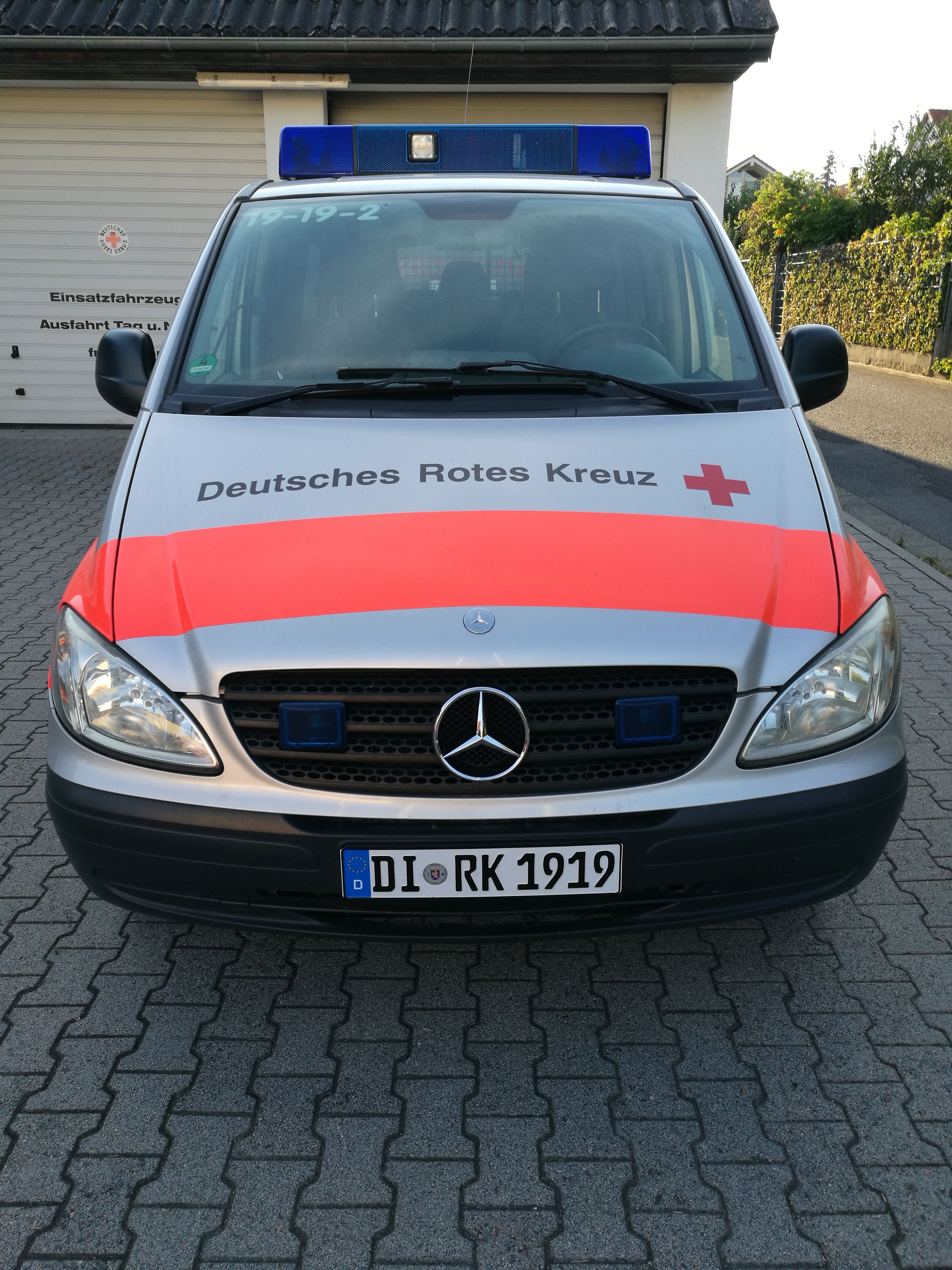 Foto: Ein DRK-Rettungssanitäter steht mit Notfallausrüstung vor einem Rettungswagen.