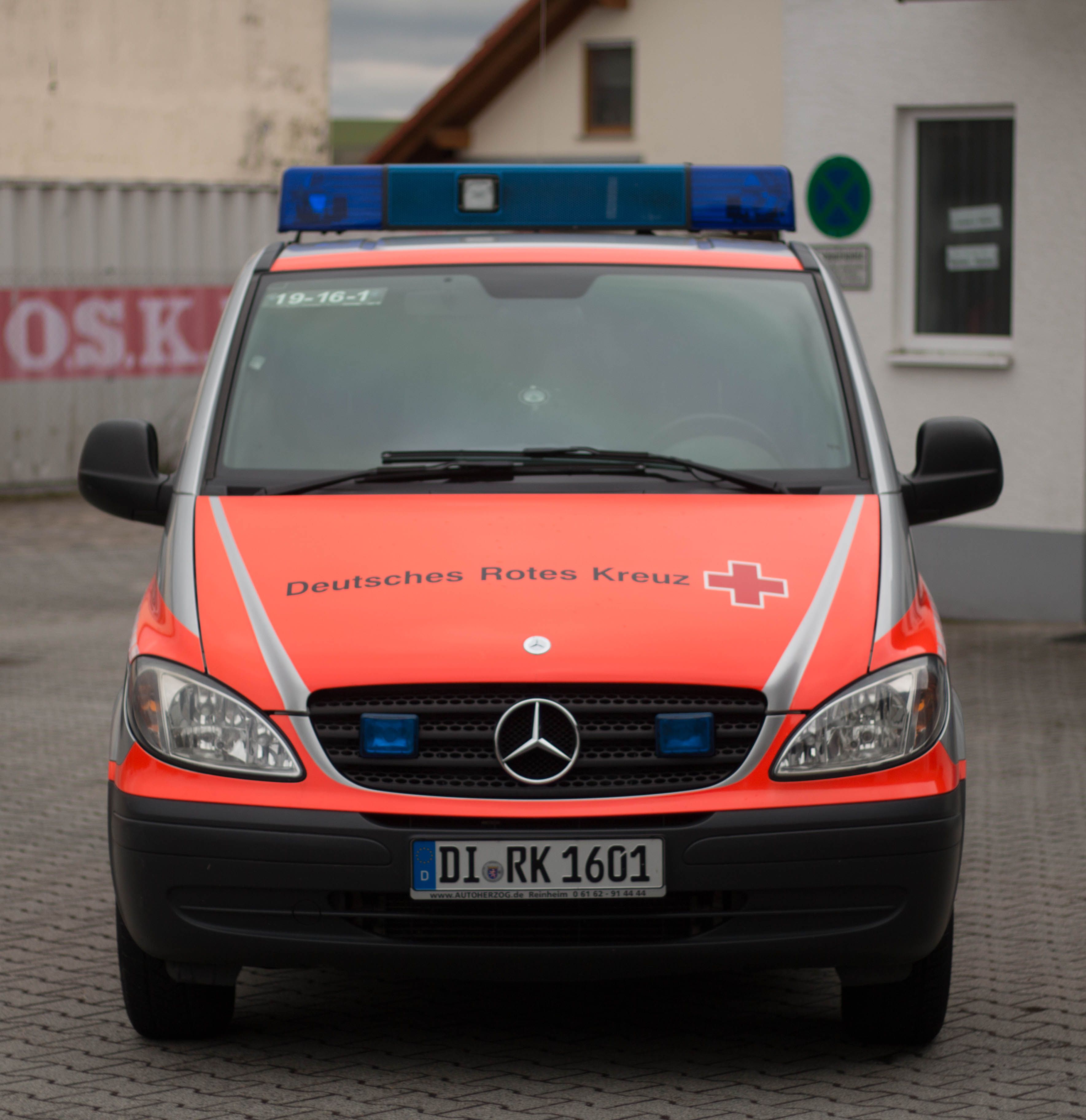 Foto: Ein DRK-Rettungssanitäter steht mit Notfallausrüstung vor einem Rettungswagen.