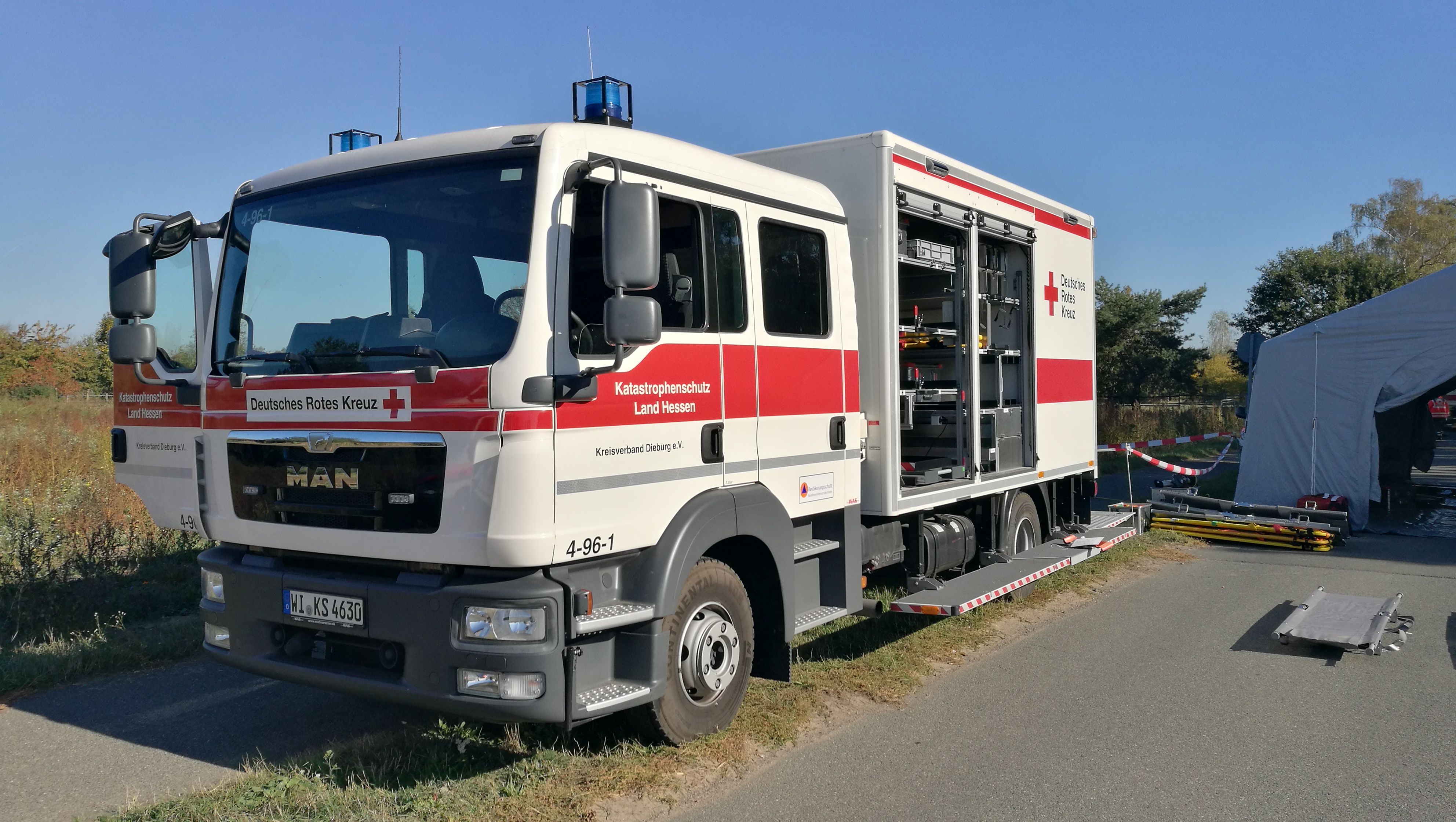 Foto: Zu sehen ist ein DRK-Rettungswagen von vorne in schneller Fahrt. Fahrer und Beifahrer konzentrieren sich auf die Fahrt.