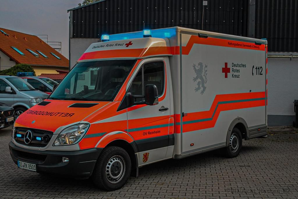 Foto: Zu sehen ist ein DRK-Rettungswagen von vorne in schneller Fahrt. Fahrer und Beifahrer konzentrieren sich auf die Fahrt.